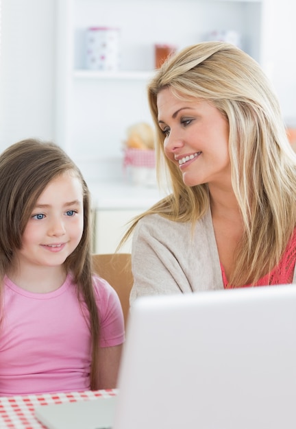 Mère souriant à la fille à l&#39;aide d&#39;un ordinateur portable