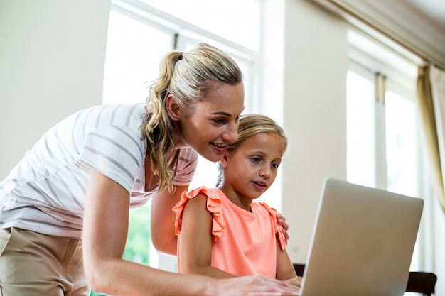 Mère souriante, à, fille, portable utilisation, chez soi