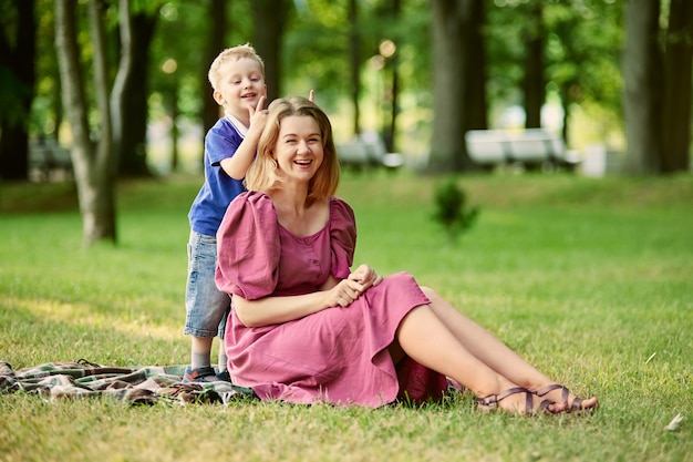 Mère souriante avec petit garçon à pied dans un parc public