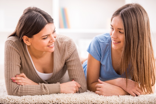 La mère souriante et sa fille adolescente sont allongées sur le sol.