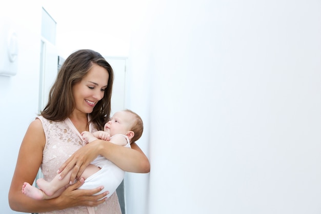 Mère souriante tenant bébé nouveau-né à la maison