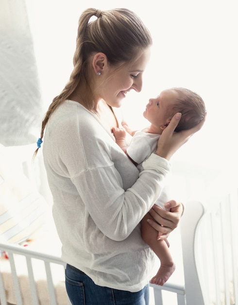 Mère souriante tenant les mains et regardant son bébé