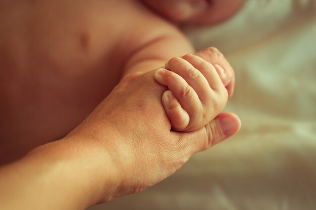 Mère tenant une main de bébé nouveau-né. Image tonique.