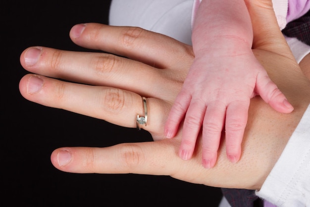 Mère tenant la main de bébé, sous fond noir