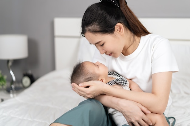 Mère tenant un nouveau-né dormant dans son bras sur un lit