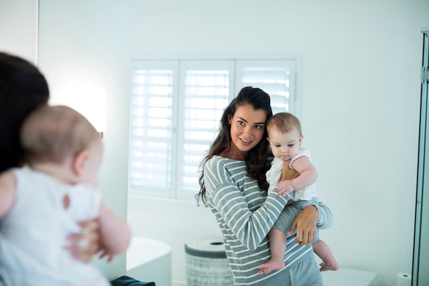 Mère tenant sa petite fille et regardant le miroir à la maison