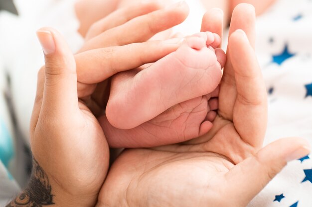 Mère tient doucement les jambes de bébé dans les mains