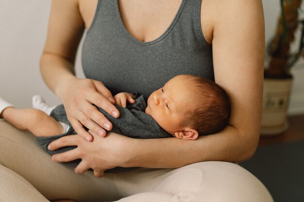 Photo la mère tient et embrasse son bébé nouveau-né à la maison bébé heureux et maman