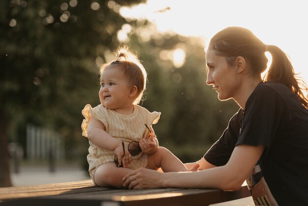 La mère tient sa jeune fille de tomber au coucher du soleil