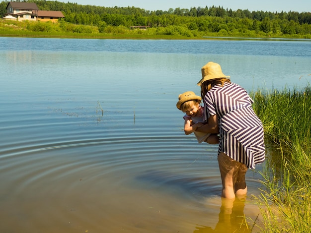 mère tient sa petite fille dans ses bras tout en nageant dans le lac, apprend à l'enfant à nager je