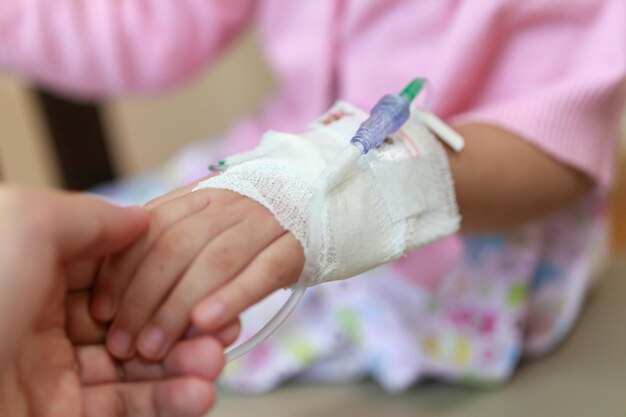 Photo une mère tient son enfant par la main avec une solution saline intraveineuse à l'hôpital