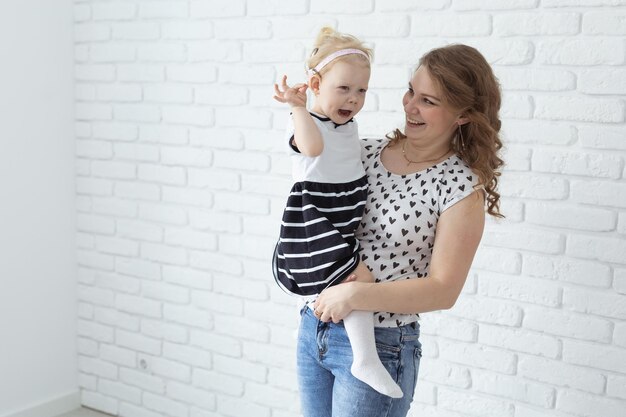 La mère tient son enfant avec des prothèses auditives et des implants cochléaires sur un mur de briques blanches avec espace de copie