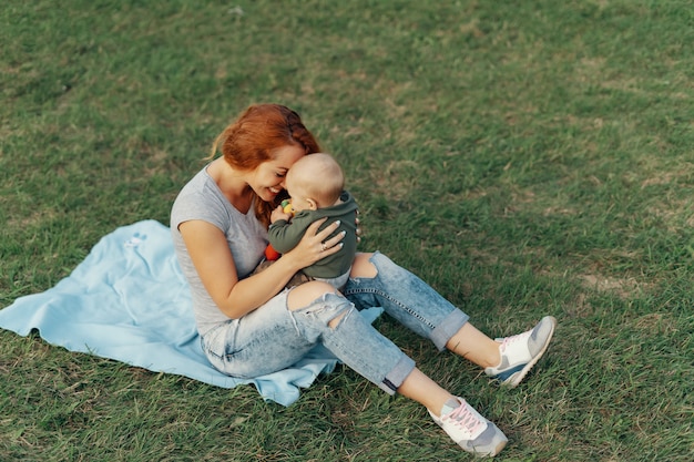 Mère tient son fils à genoux tout en jouant sur l'herbe