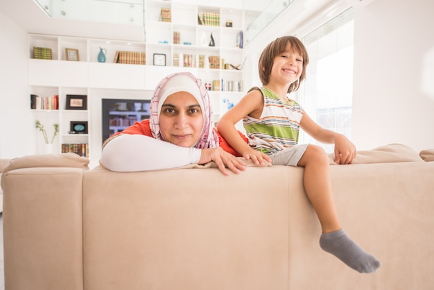 Mère traditionnelle musulmane avec petit fils mignon à la maison dans le salon