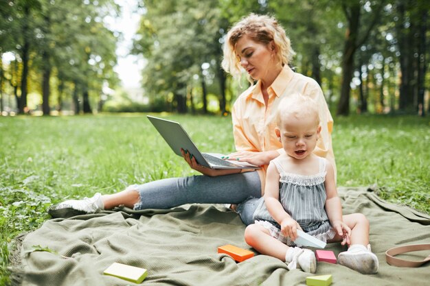 Mère travaillant en ligne dans le parc