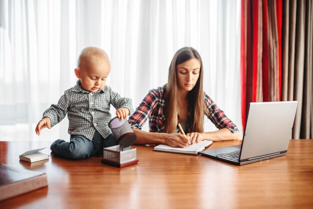 Mère travaille à la maison petit enfant l'aide