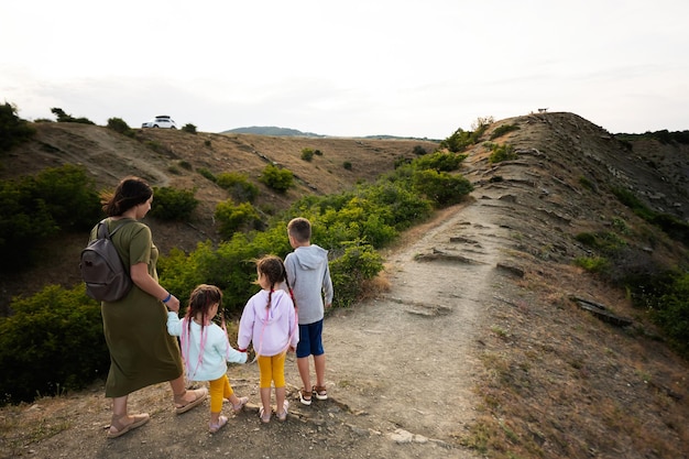 Mère avec trois enfants en randonnée dans les montagnes par une journée d'été ensoleillée