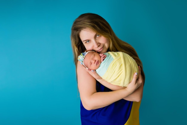 Une mère ukrainienne en drapeau bleu jaune national avec un bébé dans les couleurs pendant la guerre en gros plan