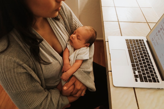 Mère Utilisant Un Ordinateur Et Tenant Son Bébé