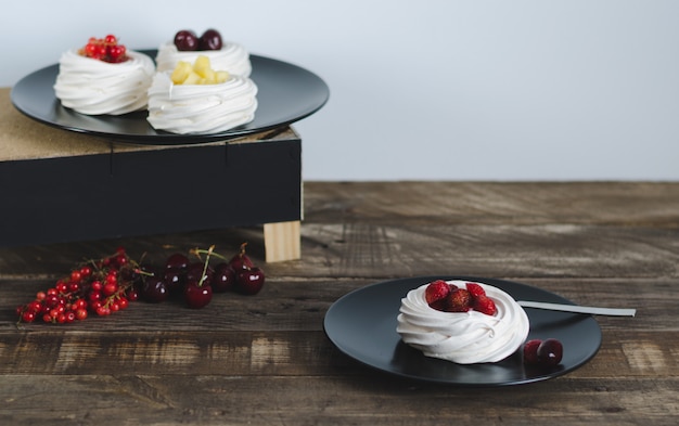 Meringue au four avec des fruits sur fond de bois foncé.