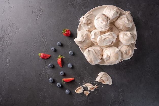 Meringue dessert populaire fait maison sur une plaque blanche sur une surface noire