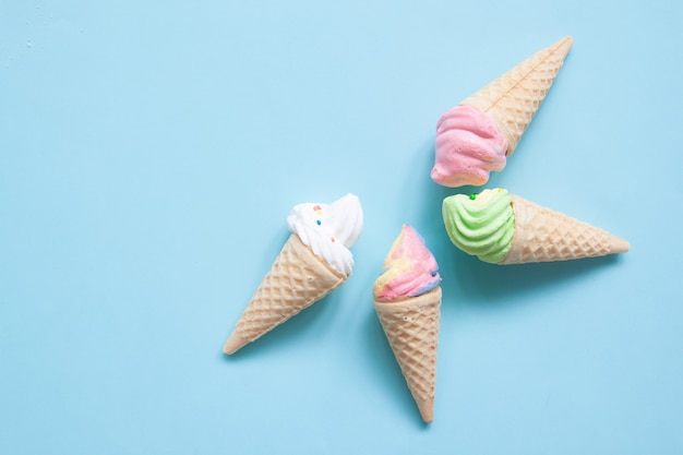 Meringue pastel sur des cornets de crème glacée sur fond bleu