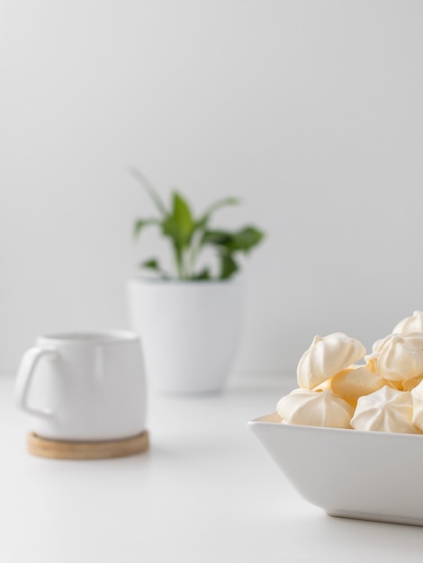 meringues à la crème dans un bol avec tasse sur fond blanc