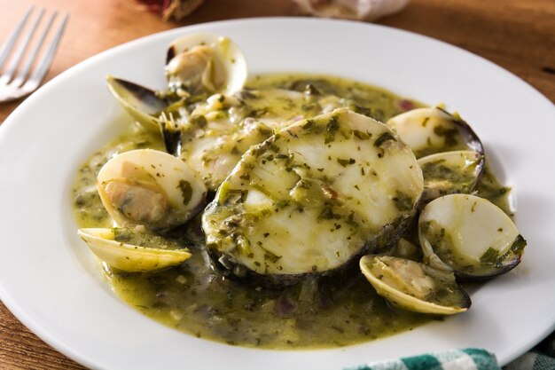 Merlu et palourdes avec sauce verte sur table en bois Recette espagnole typique