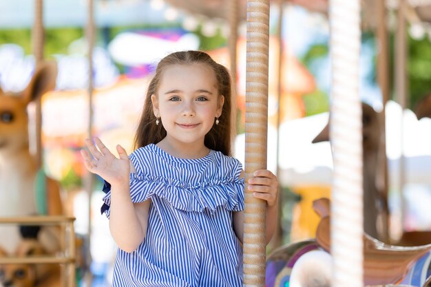 Merrygoround jolie petite fille en robe bleue jouant sur le carrousel au parc d'attractions