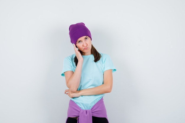 Merveilleuse dame en chemisier, bonnet debout dans une pose de réflexion et l'air concerné, vue de face.