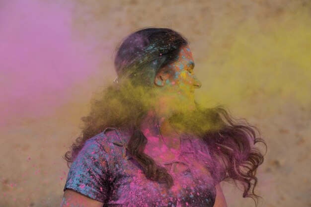 Merveilleuse femme brune profitant du festival Holi dans le désert. Femme posant avec de la peinture rose qui explose