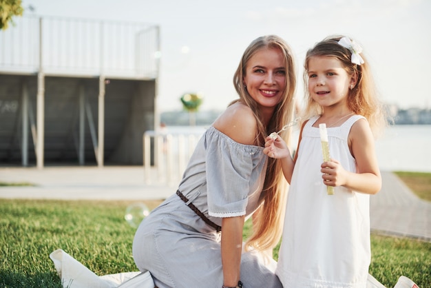 Une merveilleuse petite fille fait des bulles avec sa maman dans le parc.