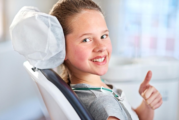 Mes dents sont prêtes à partir Portrait d'une jeune fille montrant les pouces vers le haut dans le fauteuil du dentiste