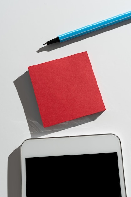 Message important présenté sur une note collante sur le bureau avec un stylo et un téléphone portable Informations cruciales écrites sur un mémo sur une table avec des données critiques sur un téléphone portable affichées