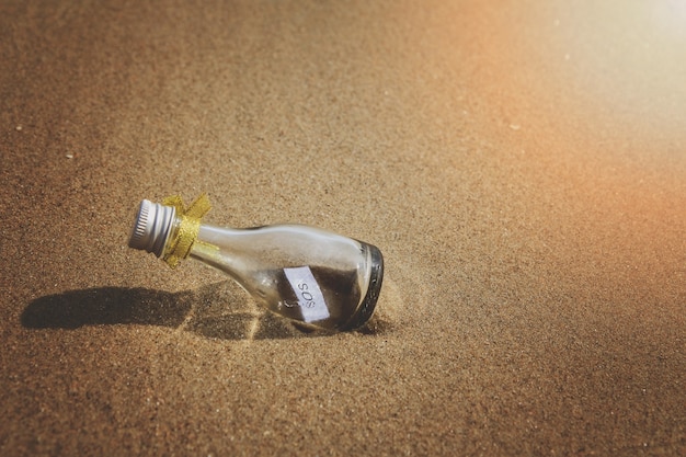 Message SOS en bouteille de verre sur la plage.