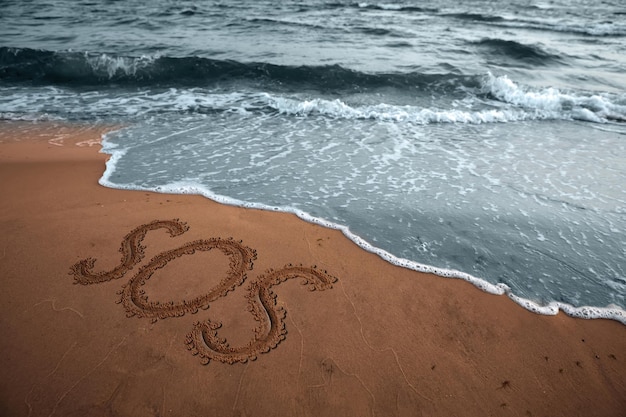 Message SOS dessiné sur une plage de sable près de la mer