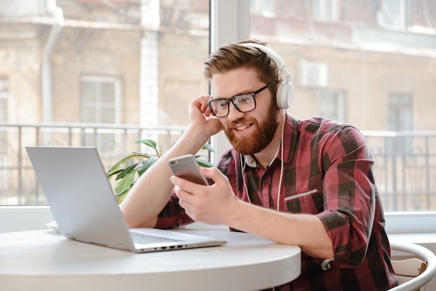 Message texte homme sur téléphone intelligent tout en écoutant de la musique