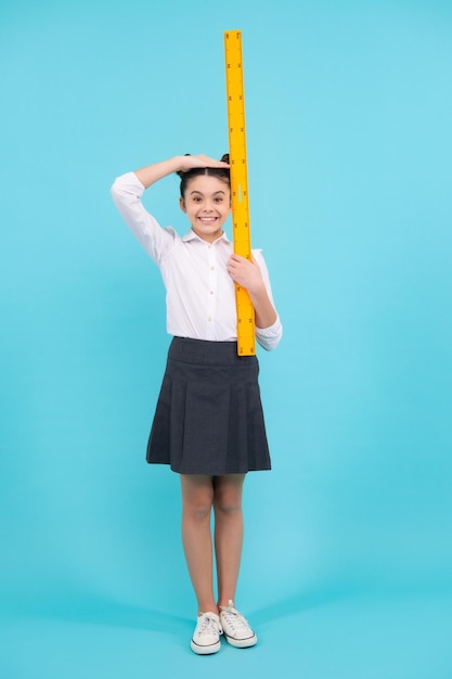 Mesure de la taille de l'enfant mesure de la croissance Adolescente écolière étudie les mathématiques ou la géométrie leçon mesure la taille Règle mathématique pour mesurer Bonne écolière positive et souriante