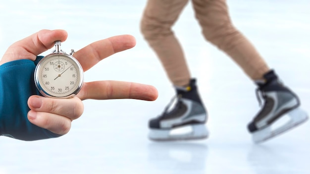 mesurer la vitesse sur patins avec un chronomètre. main avec un chronomètre sur le fond des jambes d'un homme patinant sur une patinoire