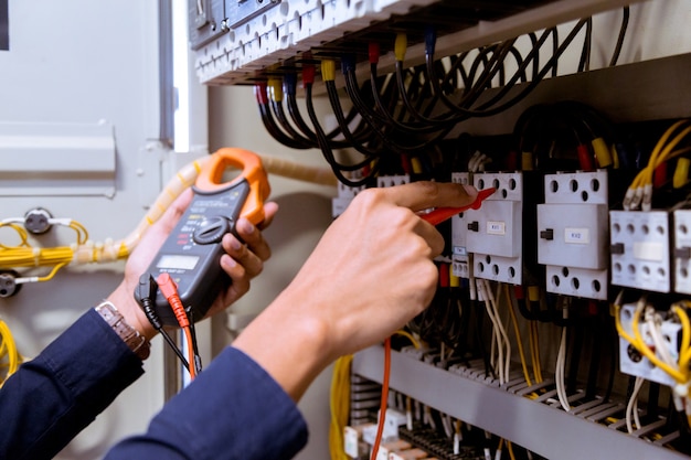 Photo mesures d'électricien avec multimètre testant le courant électrique dans le panneau de commande.