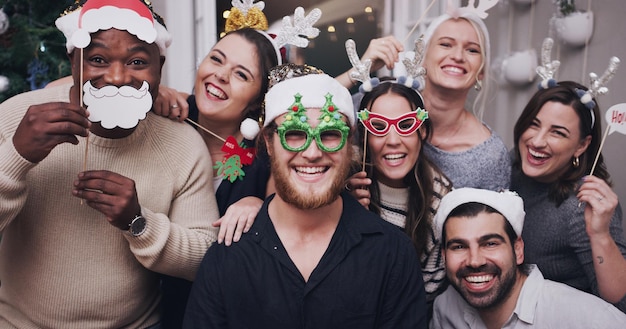 Mettez vos chapeaux de fête Noël est là Portrait d'un groupe de jeunes amis portant des chapeaux et des lunettes drôles lors d'une fête de Noël