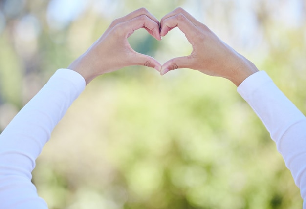 Mettez-y votre cœur. Photo recadrée d'une femme méconnaissable formant une forme de coeur tout en se tenant à l'extérieur.