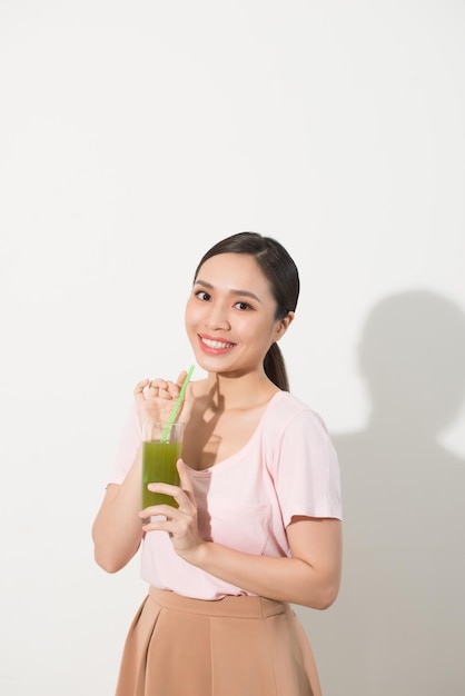 Mettre au vert. Belle jeune femme appréciant un jus de légumes de fruits crus sains. Tourné en studio.