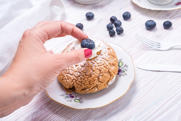 Mettre des baies à la main sur un gâteau sur fond de bois blanc