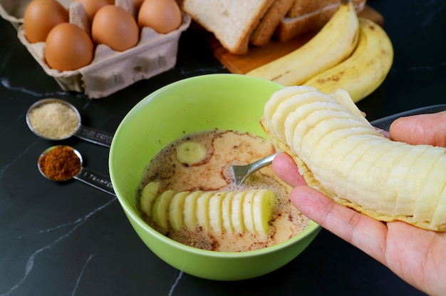 Mettre la banane fraîche et mûre à la main dans le mélange pour la cuisson du pudding au pain aux bananes
