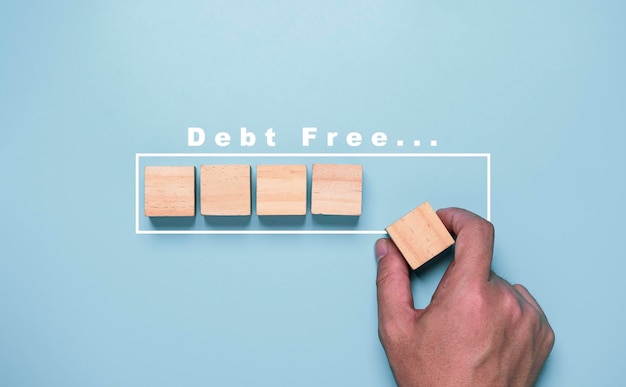 Mettre le bloc de cube en bois à la main pour le concept de résultat progressif de la dette.