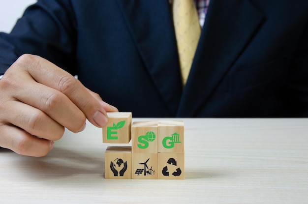 Mettre à la main des cubes en bois avec le symbole de gouvernance sociale environnementale ESG sur l'espace de copie de tableConcepts d'entreprise