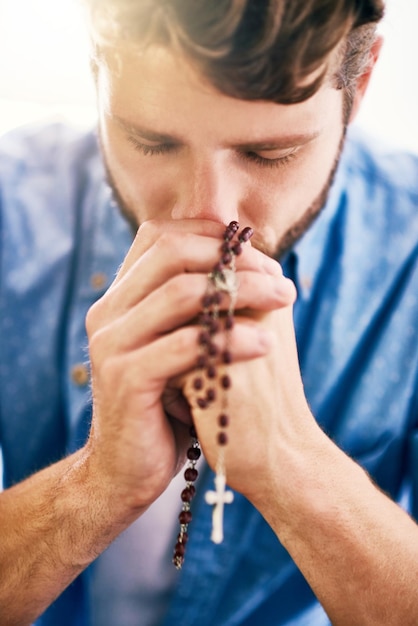 Mettre sa foi en premier Photo recadrée d'un jeune homme tenant son chapelet en priant