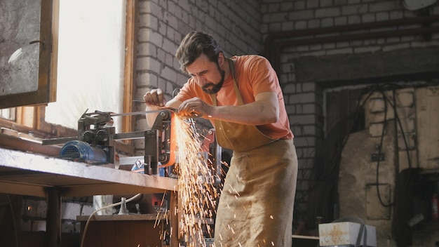 Meulage d'outils métalliques avec des étincelles - atelier de forge, tir de curseur