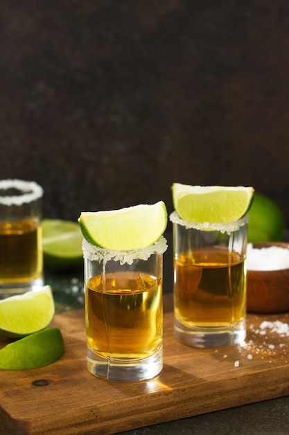 Mexican Gold Tequila tourné avec de la chaux et du sel sur fond de pierre sombre Copy space